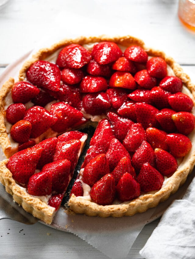 custard tart with glazed strawberries arranged on top.