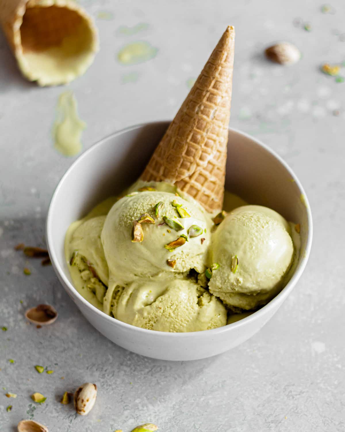 homemade pistachio ice cream in a bowl with a waffle cone.