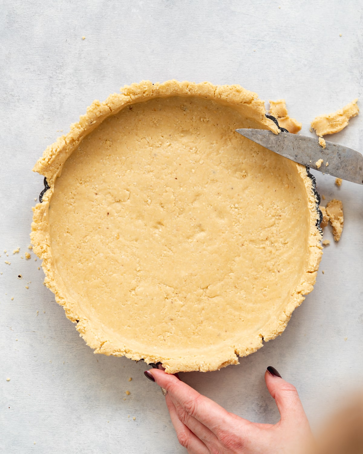 trimming the edges off a tart crust with a knife.