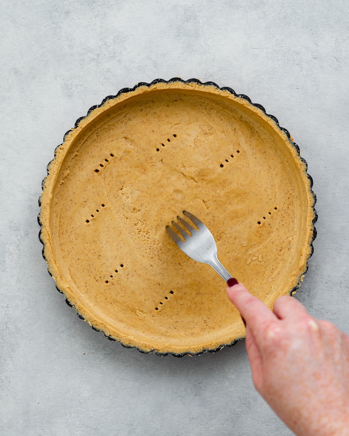 piercing holes into a tart shell with a fork.