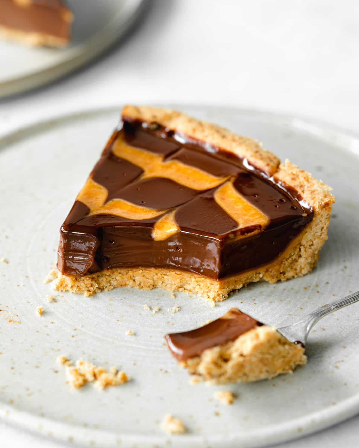 slice of peanut butter chocolate ganache tart on a plate with a fork.