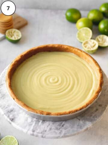 vegan key lime pie just filled with freshly made lime curd and fresh squeezed limes in the background.