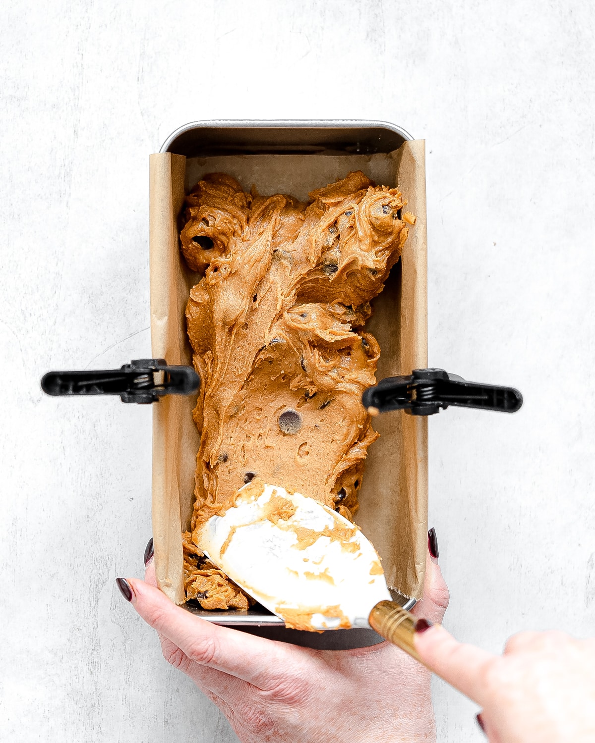 pressing cookie dough fudge into a loaf pan with a spatula.