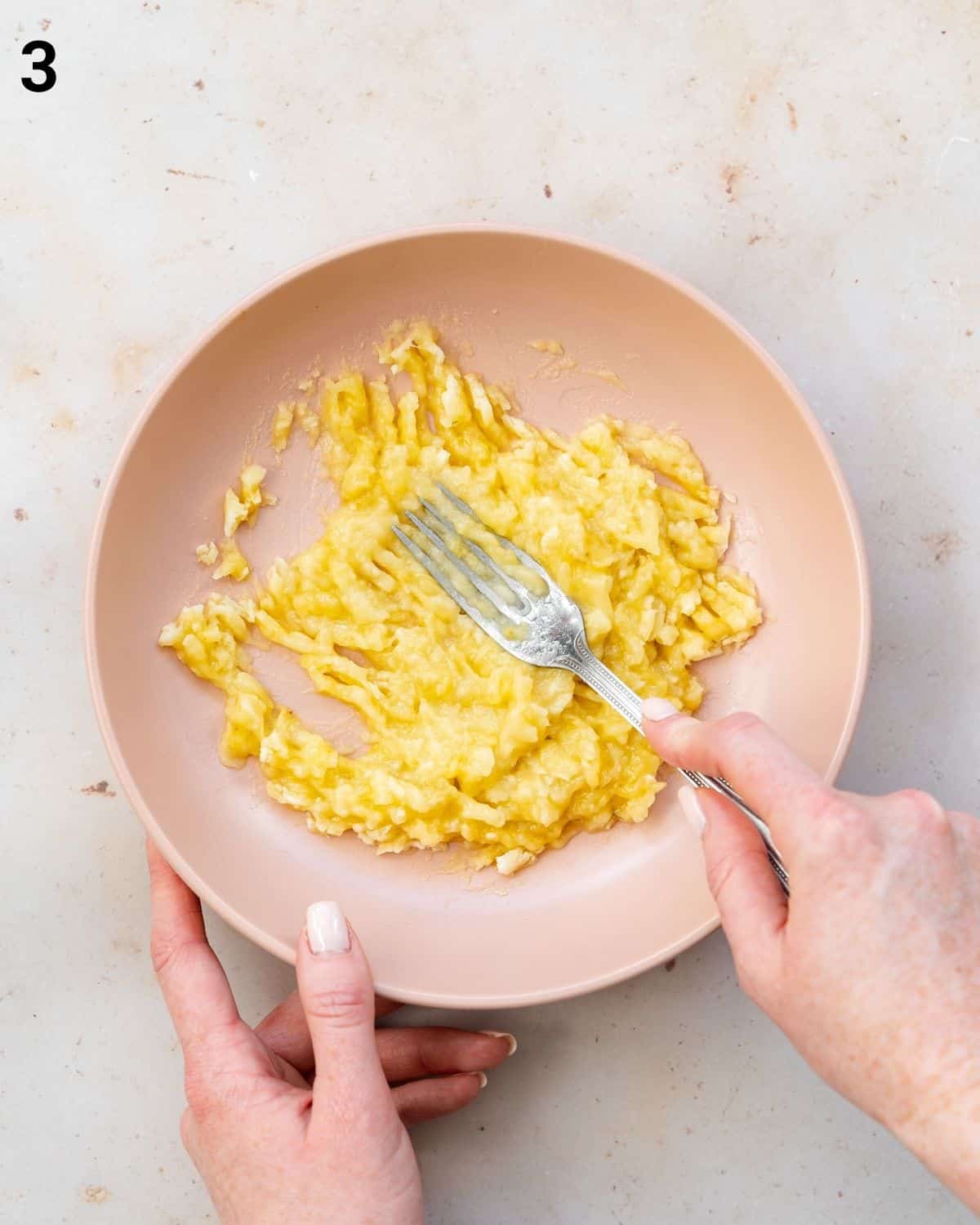 mashing bananas in a bowl using a fork.
