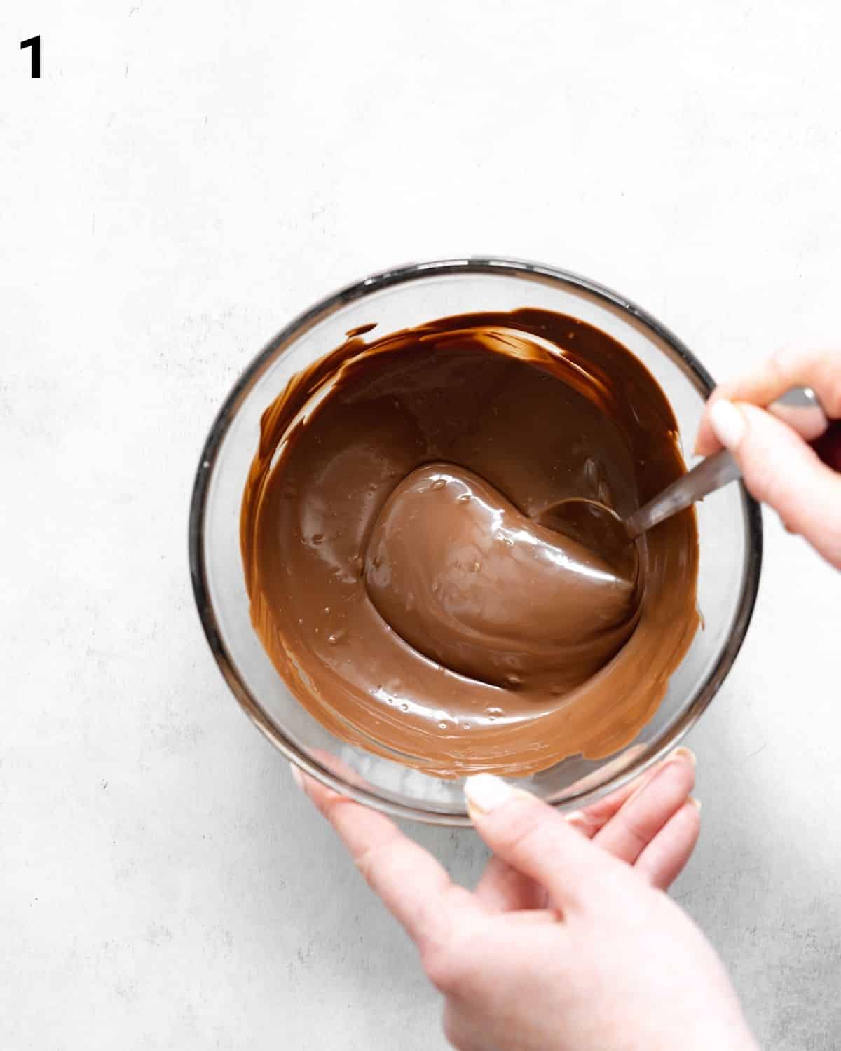 stirring melted chocolate in a bowl.