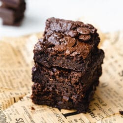 stack of fudgy gooey vegan brownies on brown paper.