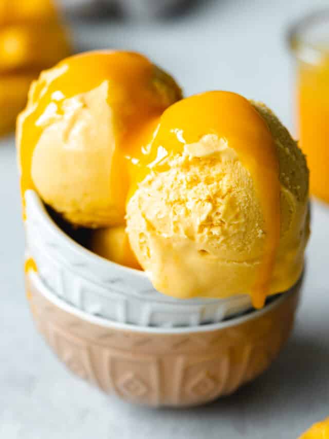 closeup of scoops of mango ice cream with mango pulp sauce.