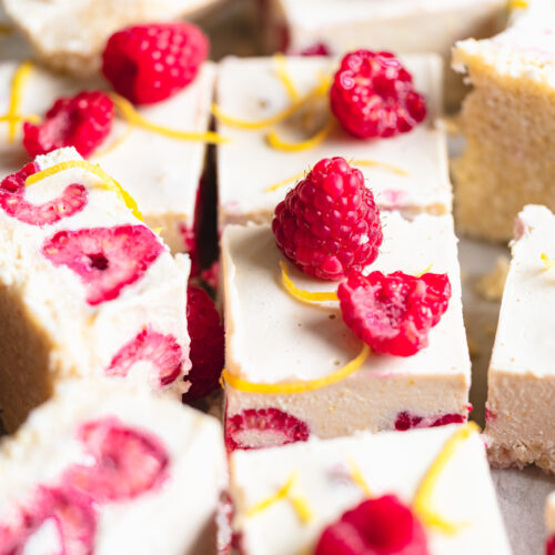close up of lemon cheesecake bars with raspberries.