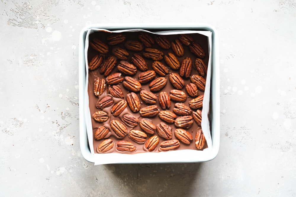 pecans on top of chocolate caramel slices.