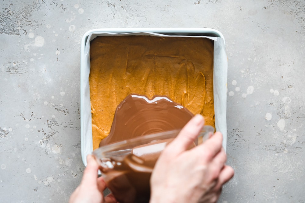 chocolate pouring over pumpkin caramel in a pan.