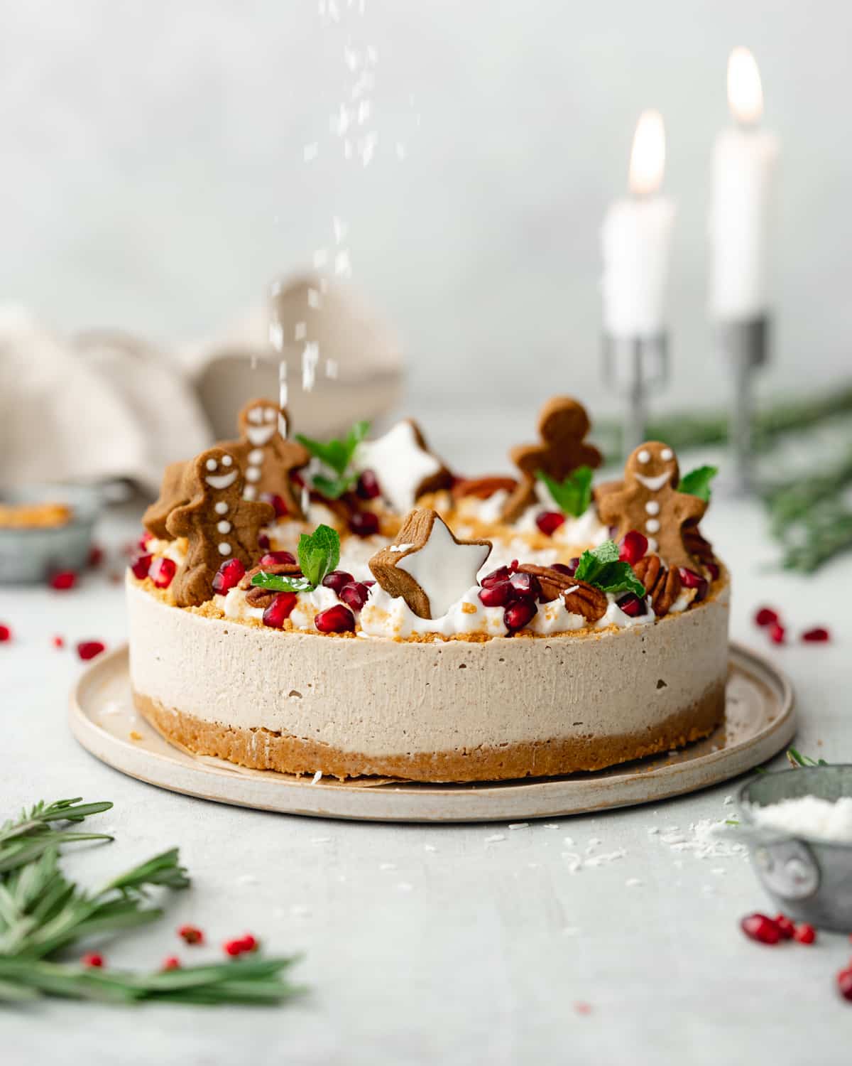 gingerbread cheesecake with gingerbread cookies on top and lit candles in the background.