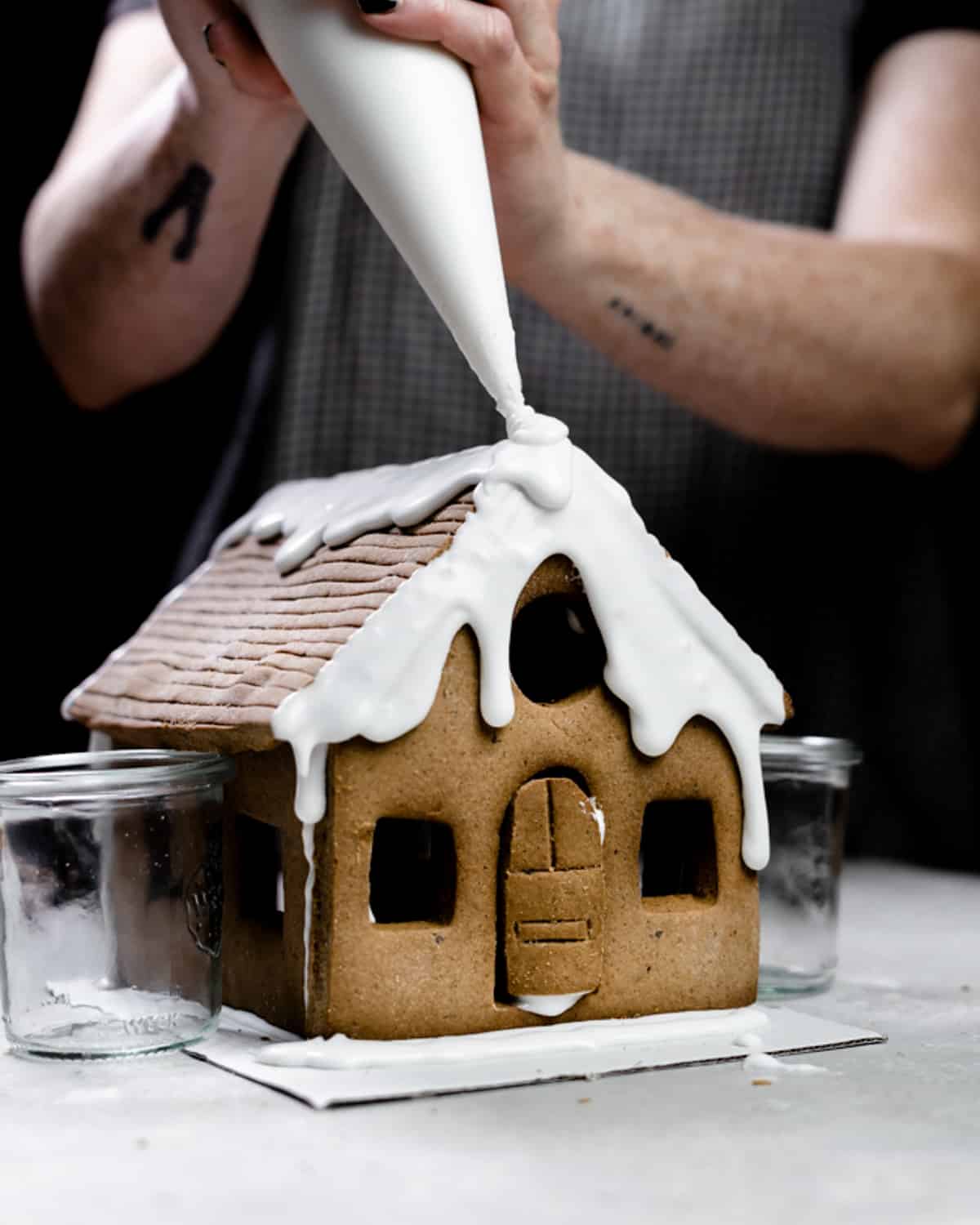 pouring royal icing over gingerbread house.