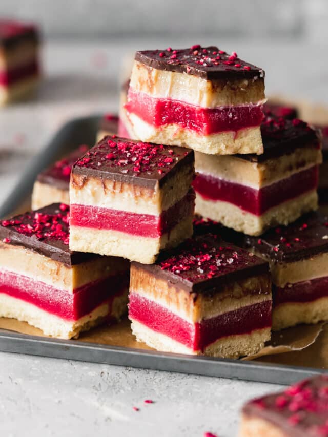 caramel slices with a bright fuchsia strip of raspberry jelly stacked on top of each other.