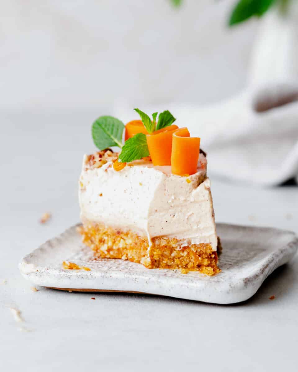 slice of no-bake carrot cake cheesecake on a plate with mint leaves on top.