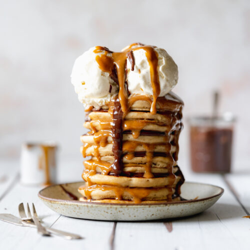 stack of pancakes with 2 scoops of ice cream, chocolate sauce and caramel sauce.