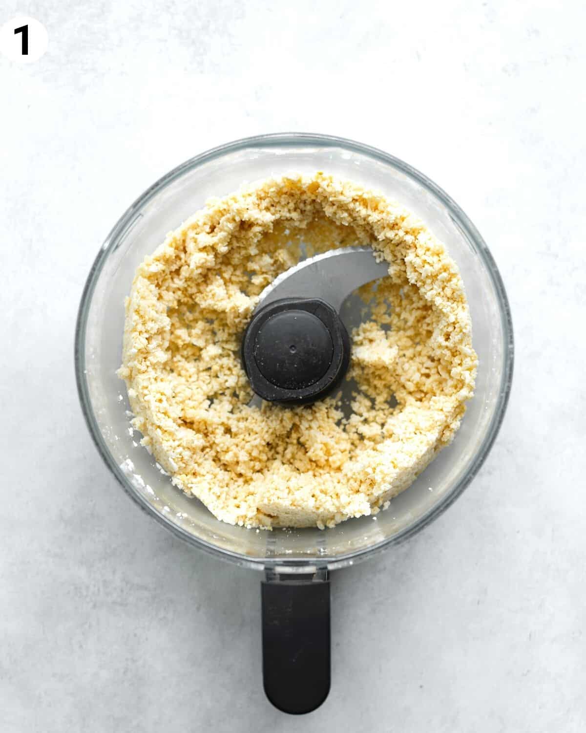 top down view of mango cheesecake crust ingredients in a food processor.