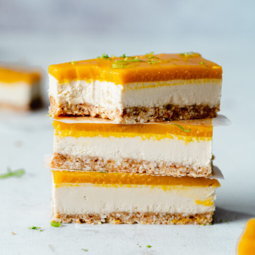 stack of mango cheesecake bars against a light blue background.