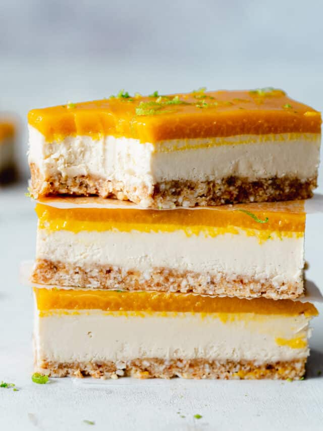 stack of mango cheesecake bars against a light blue background.