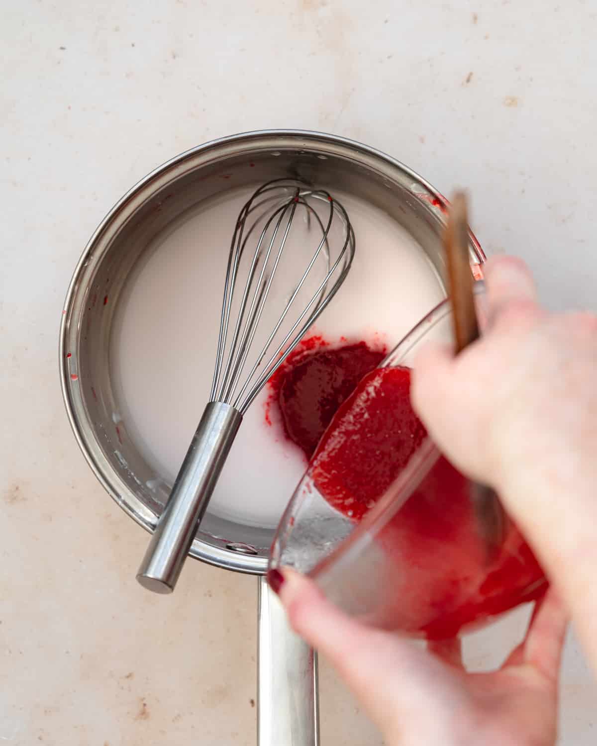 pouring raspberry coulis into a saucepan.