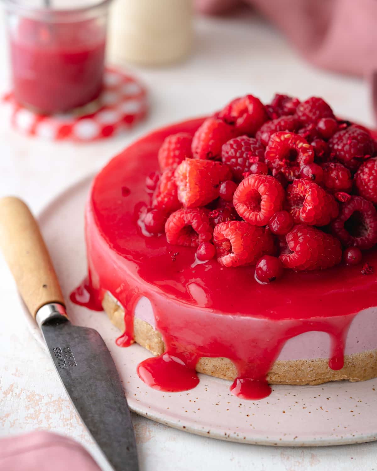 vegan raspberry cheesecake with raspberry sauce and fresh raspberries on top.