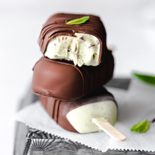 stack of mint chocolate chip ice cream bars on metal tray with fresh mint.