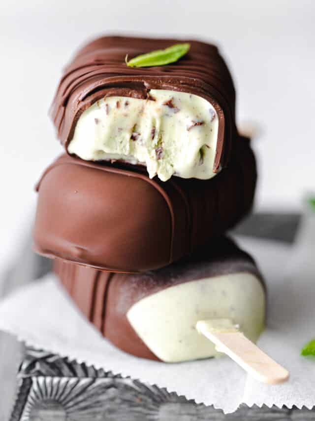 stack of mint chocolate chip ice cream bars on metal tray with fresh mint.