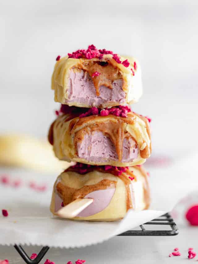 stack of white chocolate raspberry ice cream bars on cooling rack with almond butter drizzle.
