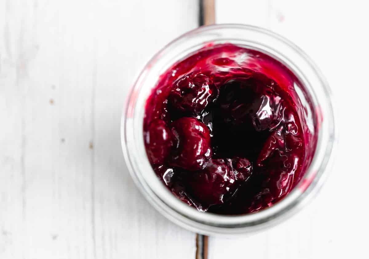 vegan cherry jam in a jar on a white wooden background