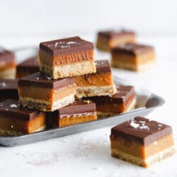 peanut butter millionaire shortbread bars stacked on metal tray.