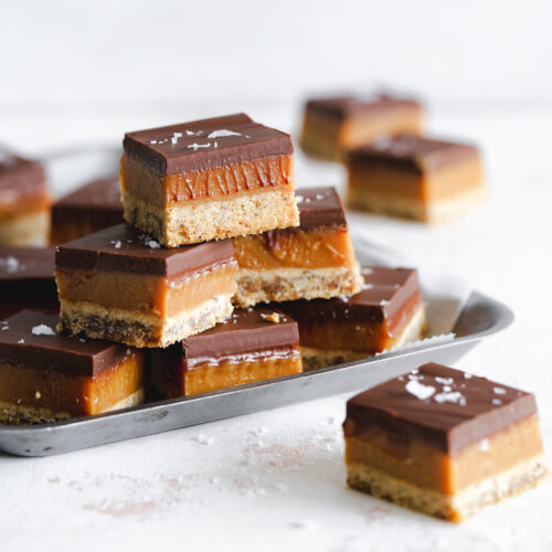 peanut butter millionaire shortbread bars stacked on metal tray.