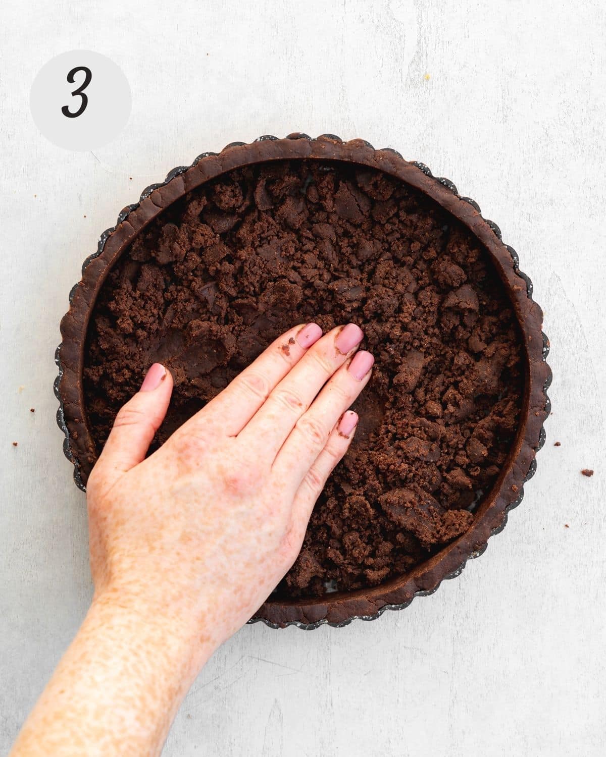 hand pressing pastry into a tart tin.