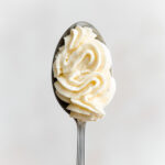 piped vanilla bean cream cheese frosting on a spoon.