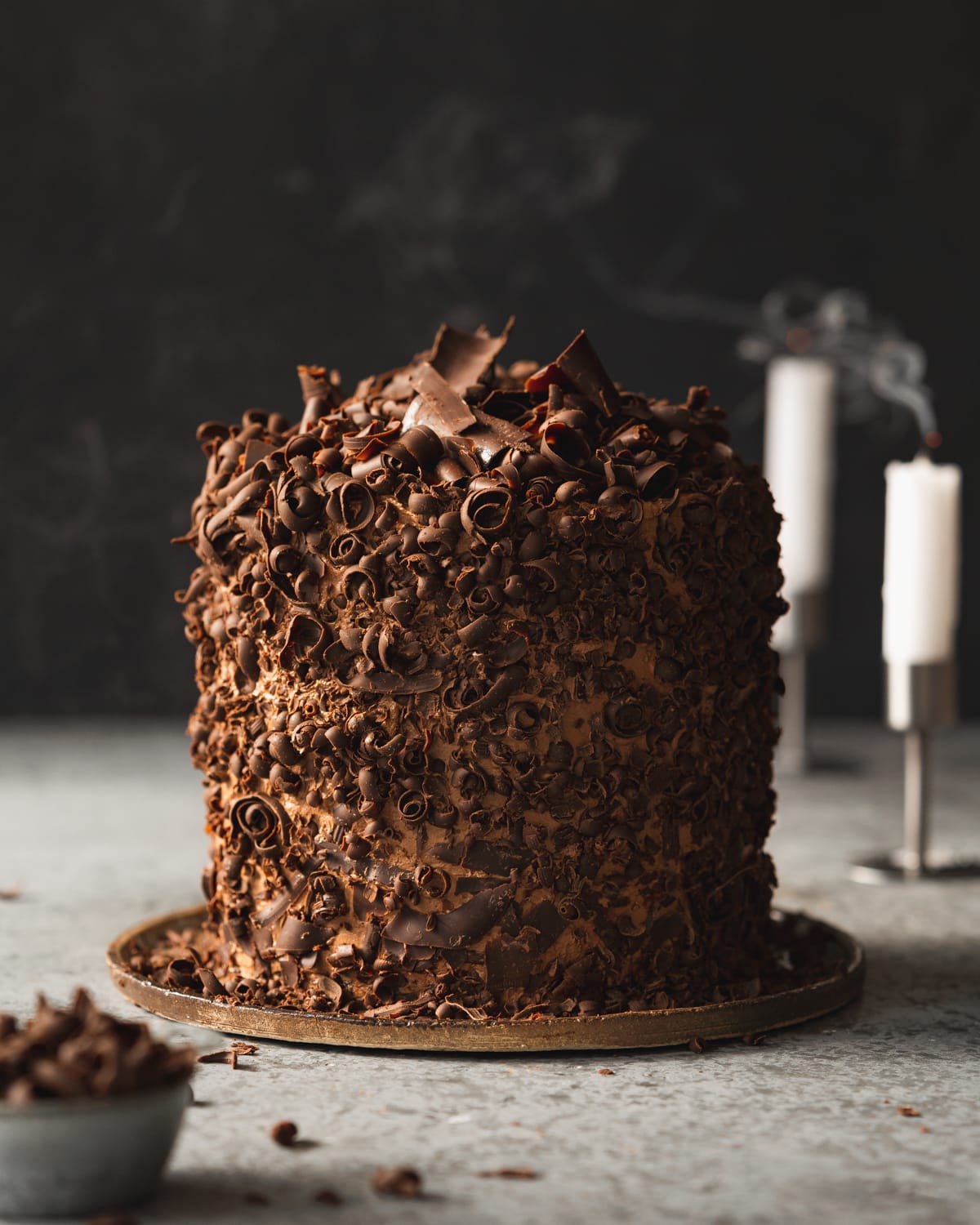 vegan chocolate cake with chocolate shavings and dark background.