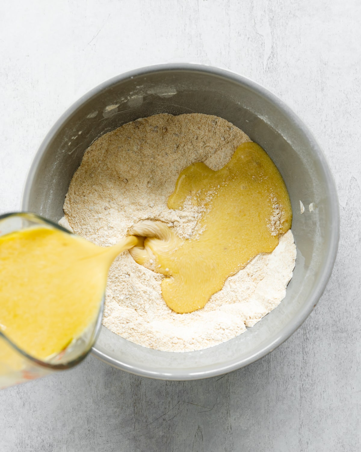 pouring wet ingredients into a bowl with dry ingredients.