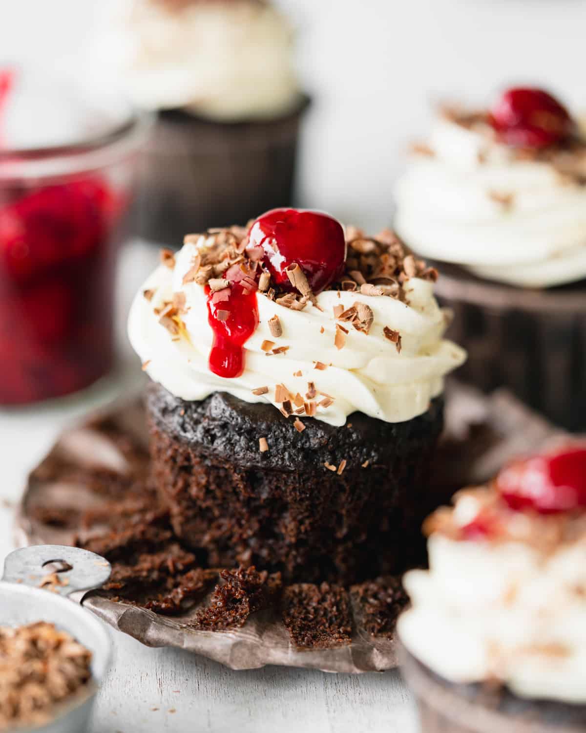 chocolate cupcakes with buttercream and cherries on top.