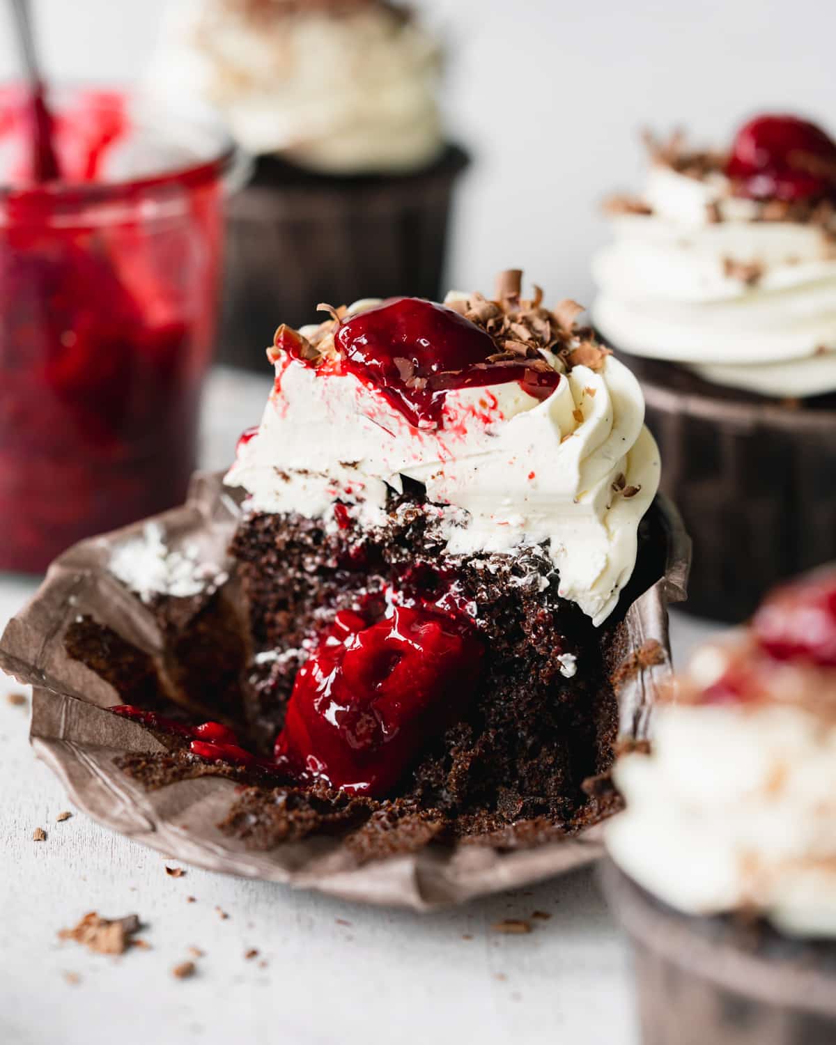 black forest cupcake sliced in half with cherry filling oozing out.