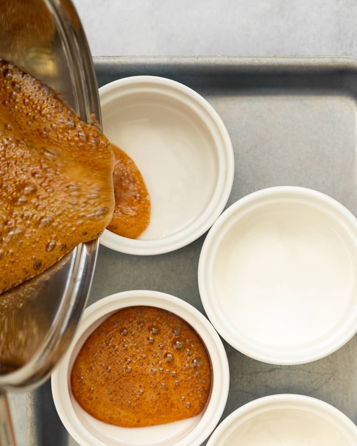 pouring caramel sauce into ramekins.