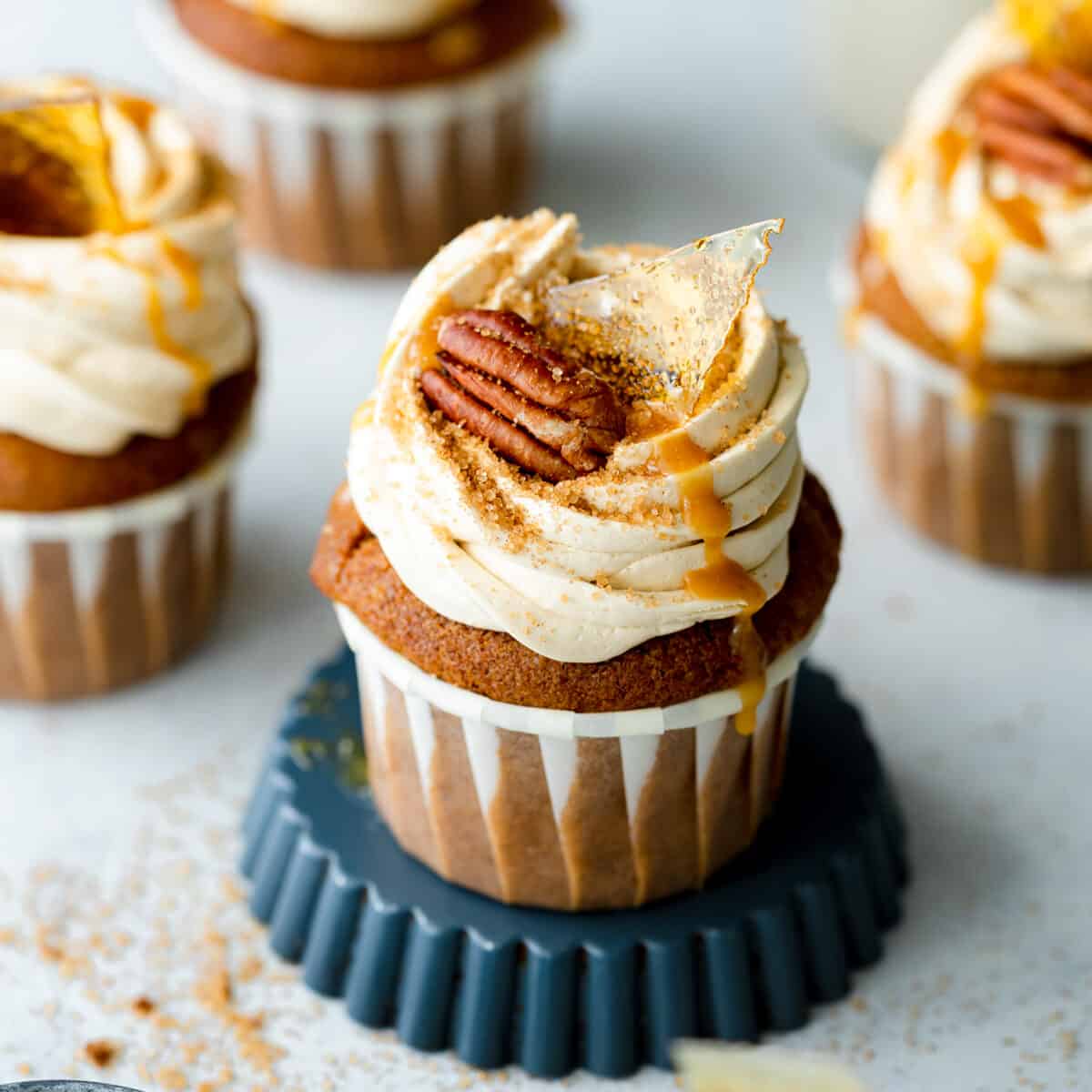 frosted cupcakes with pecans and caramel sauce on top.