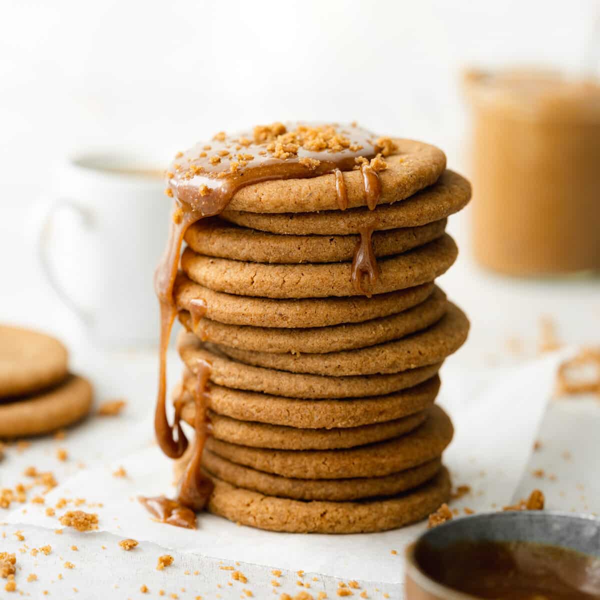 stack of homemade biscoff cookies with cookie butter dripping over them and coffee in the background.