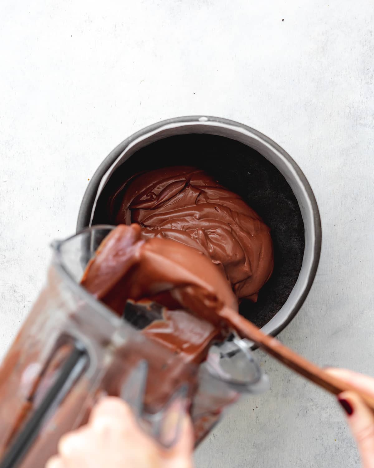 jug pouring chocolate cheesecake filling into a cake tin.