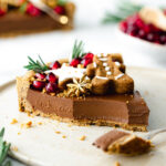 slice of chocolate tart with gingerbread cookies and pomegranate seeds on top.