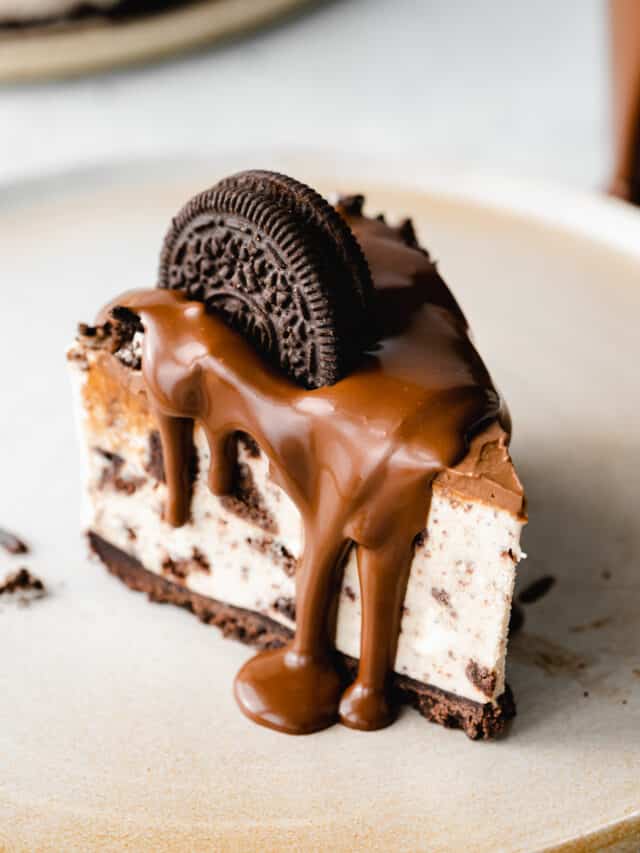 slice of vegan oreo cheesecake with chocolate ganache poured on top and an oreo cookie.