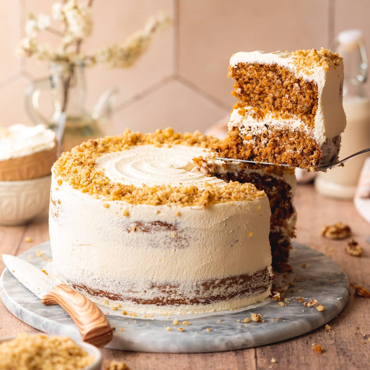 layered vegan carrot cake with dairy-free cream cheese frosting on a plate.