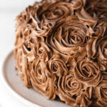chocolate cake with chocolate buttercream roses piped on it.