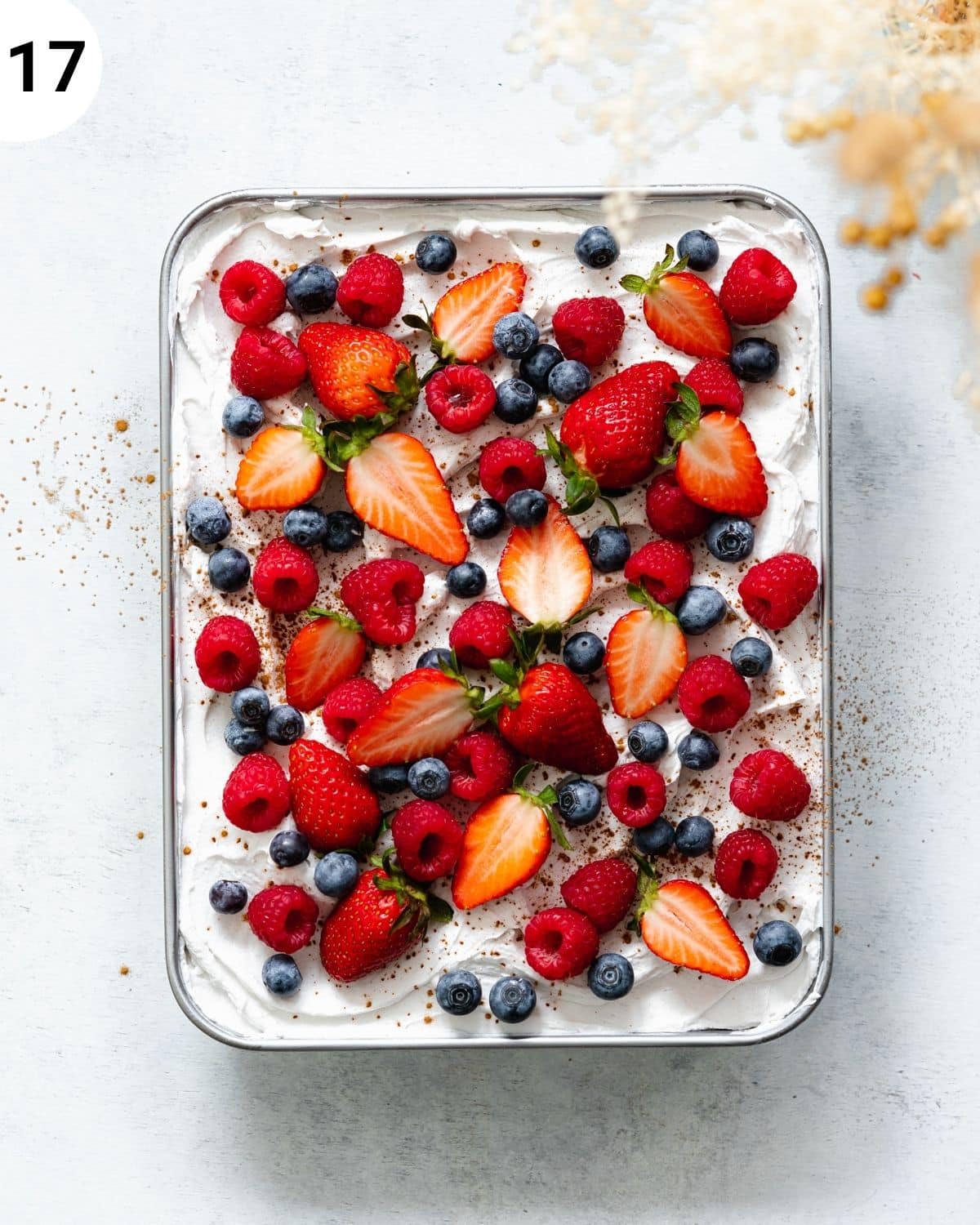 top down view of tres leches with coconut cream topping and fresh blueberries, raspberries and strawberries.