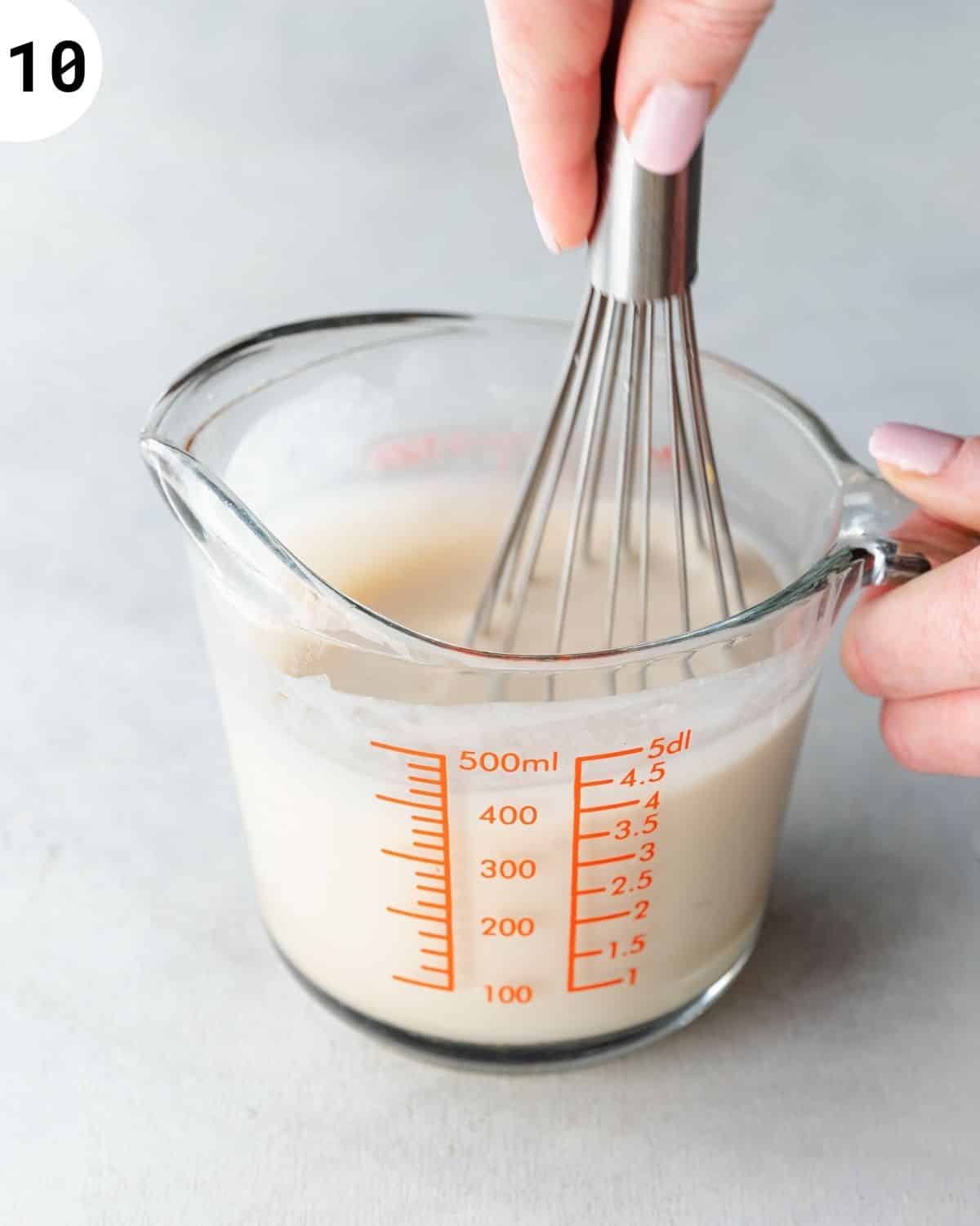 whisking tres leches syrup in a jug.