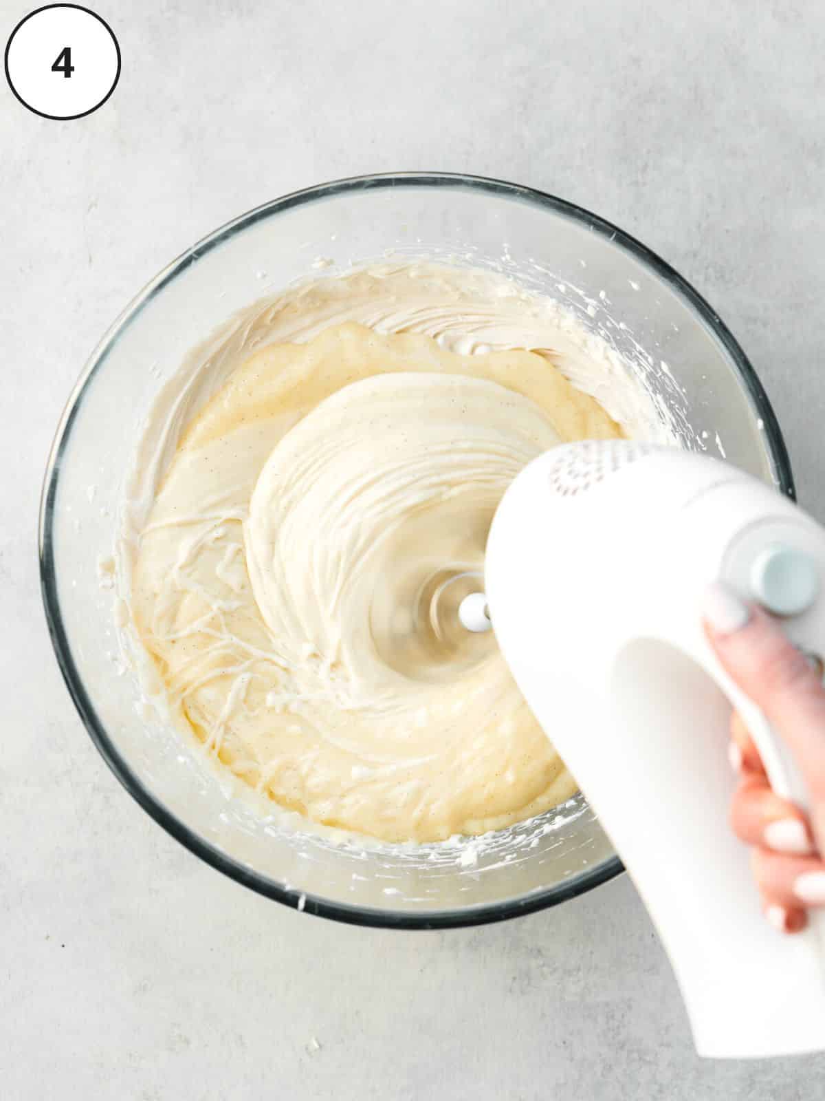 whisking vegan vanilla ice cream in a large clear mixing bowl.