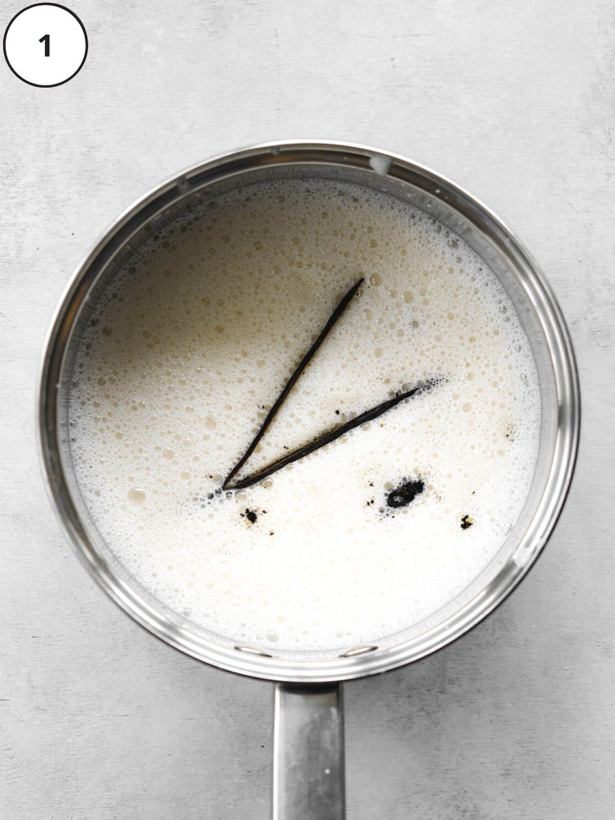 soy milk and a whole vanilla pod split down the middle in a saucepan, to make a custard base for vegan ice cream.