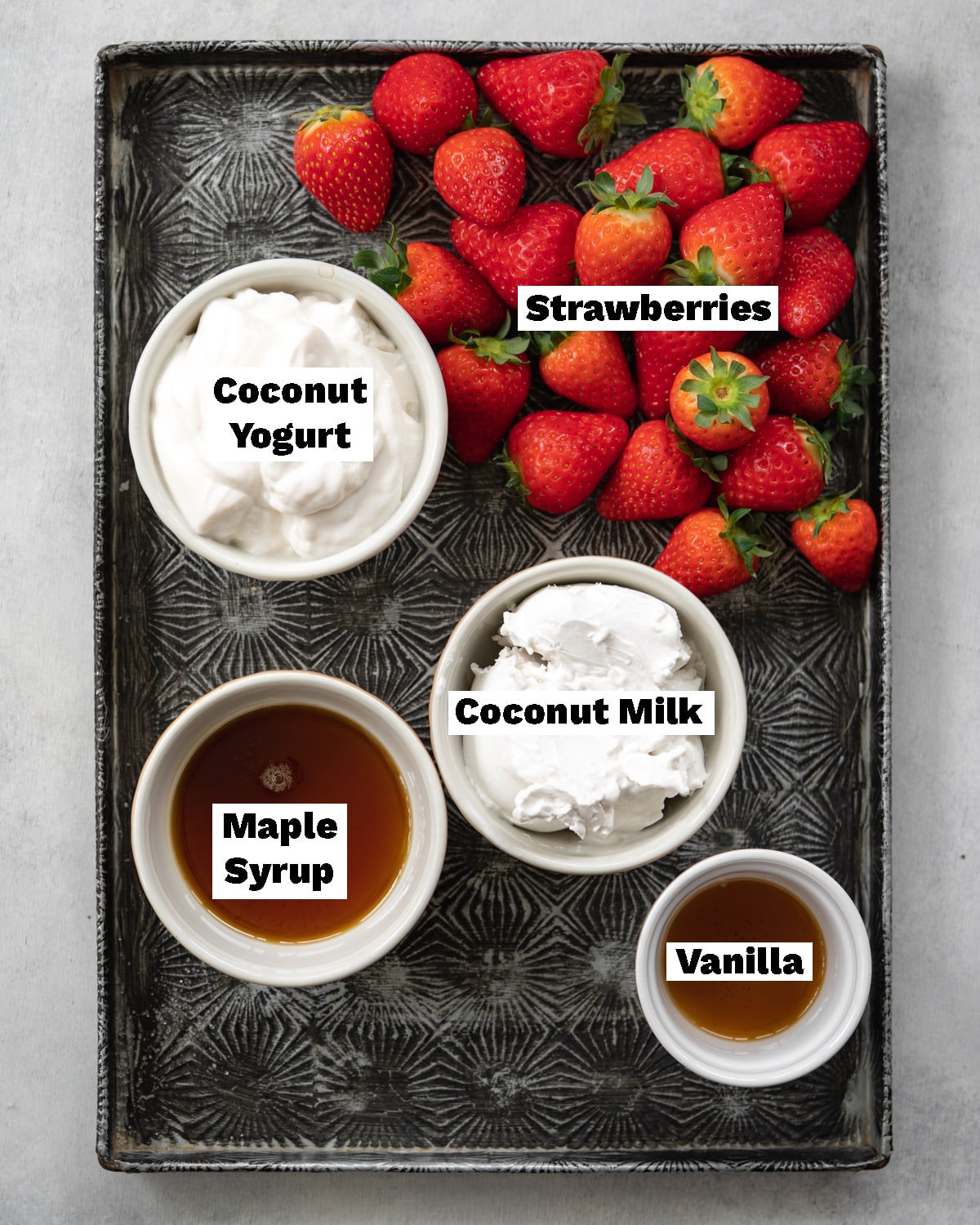 ingredients to make strawberry popsicles measured out on a tray.