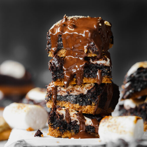 stack of brownies with marshmallows and a graham cracker with chocolate sauce dripping over them.